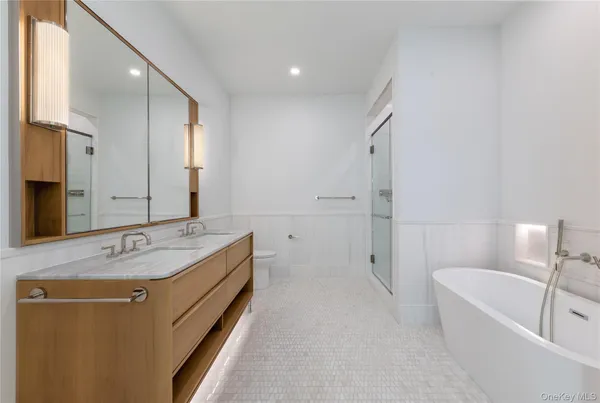 a spacious bathroom with a tub sink and mirror