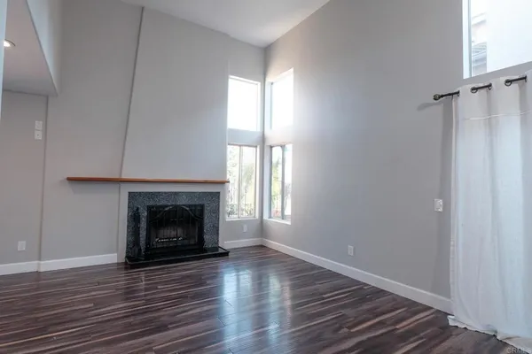 a view of an empty room with wooden floor fireplace and a window