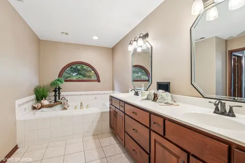 a bathroom with a double vanity sink mirror and bathtub