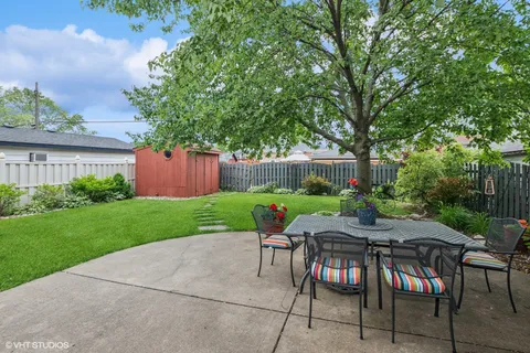 a patio with table and chairs and potted plants