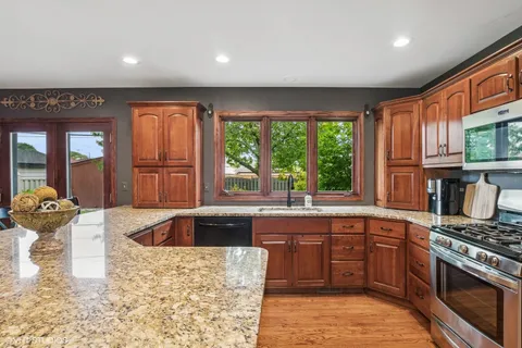 a kitchen with stainless steel appliances granite countertop a stove a sink and a microwave