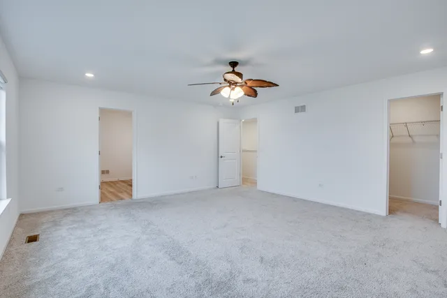 an empty room with a chandelier fan and windows