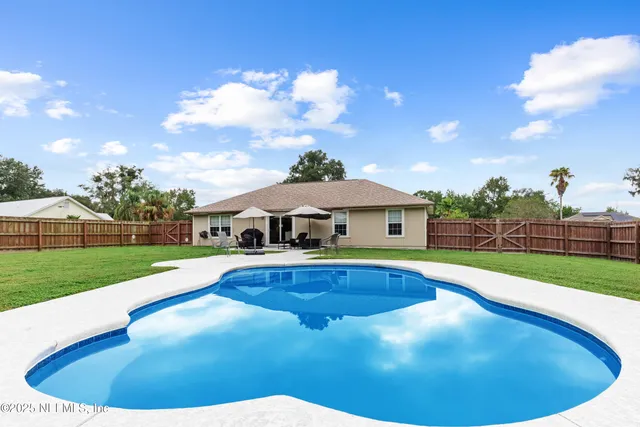 a view of pool with lawn chairs and a yard