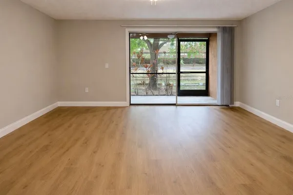 a view of an empty room with wooden floor and a window