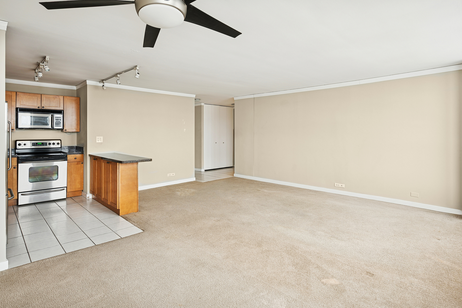 655 West Irving Park Road, Unit 3706 Chicago, IL 60613 - Photo 6 of 16 an empty room with ceiling fan and kitchen view
