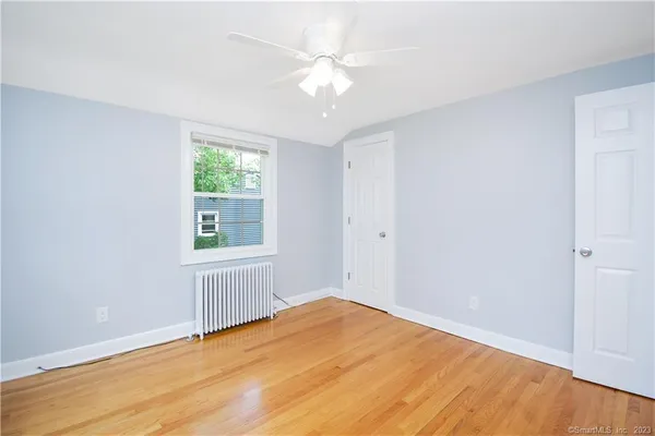 a view of empty room with wooden floor and fan