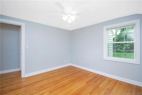 an empty room with wooden floor fan and windows