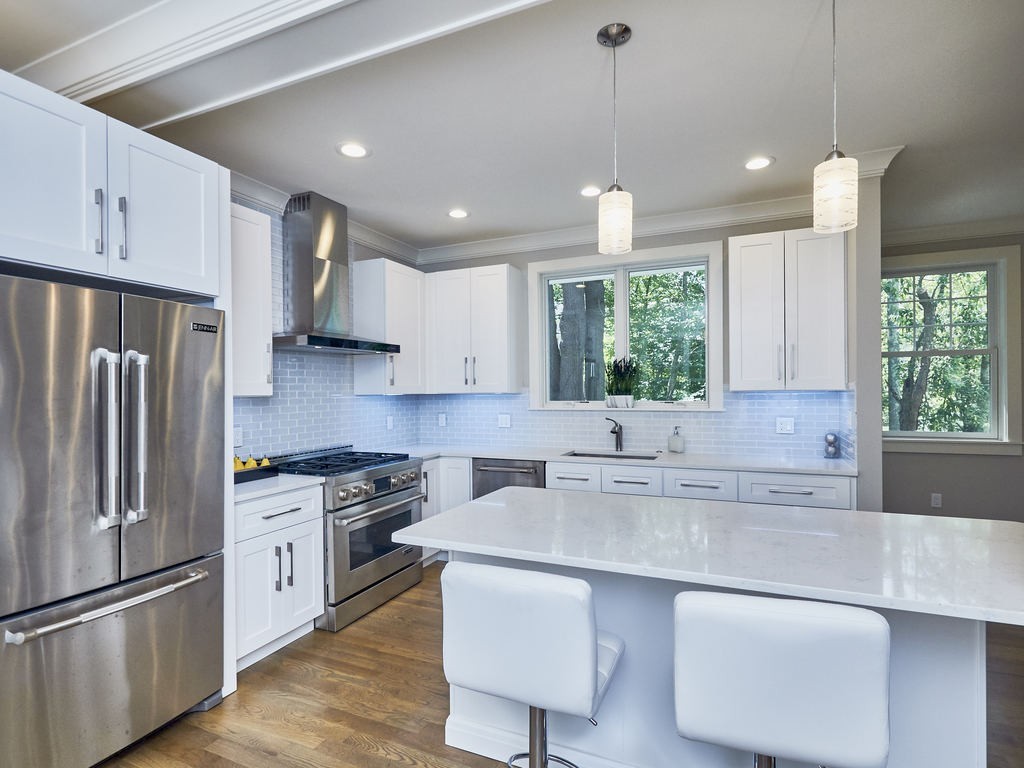 a kitchen with kitchen island granite countertop a sink a counter space appliances and cabinets