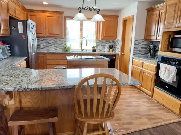 a kitchen with stainless steel appliances granite countertop a stove a sink and a dining table with granite countertops