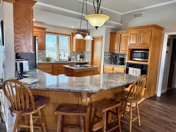 a kitchen with stainless steel appliances granite countertop a table chairs and a refrigerator