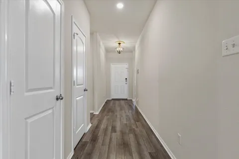 a view of a hallway with wooden floor and a bathroom