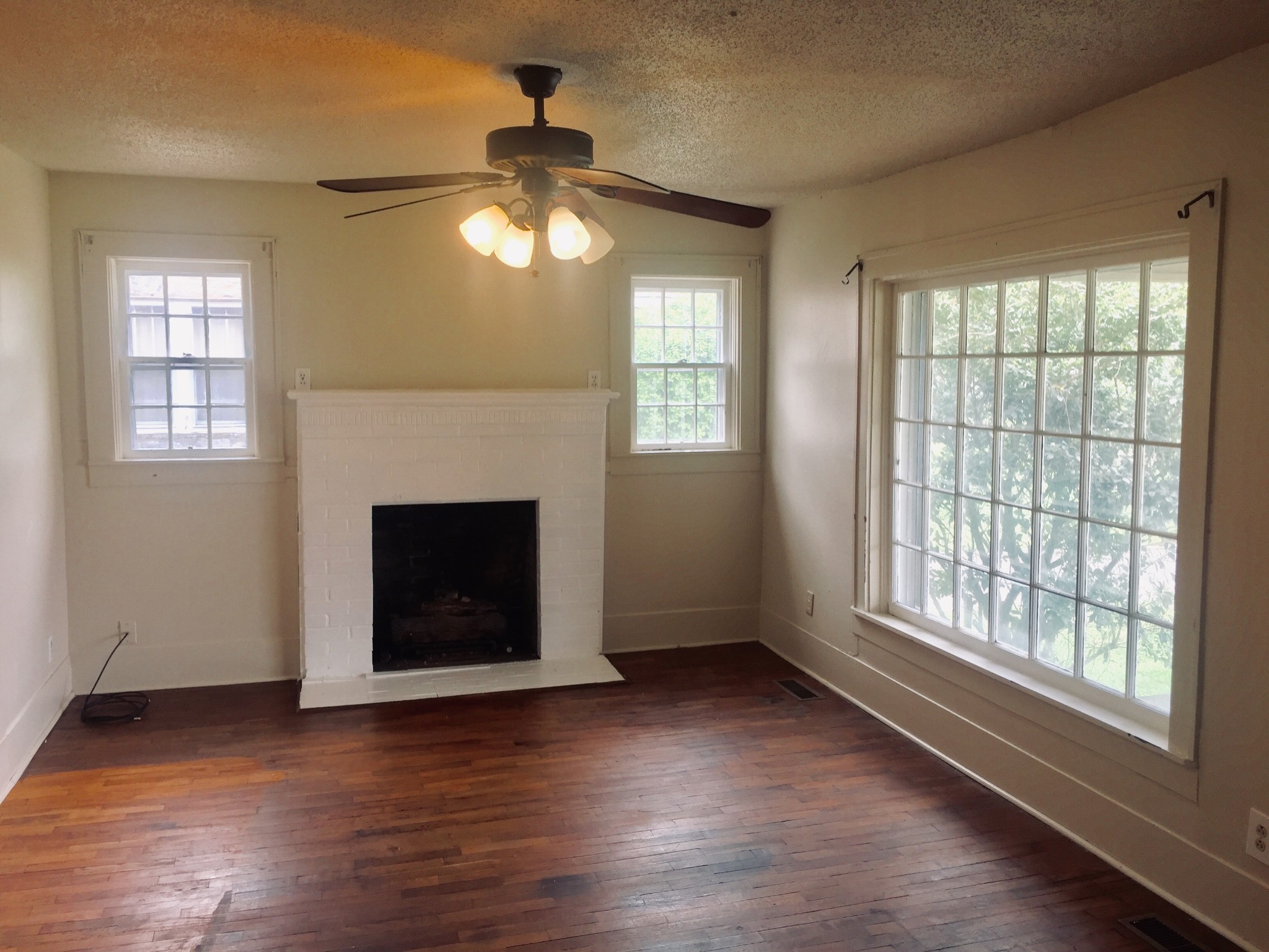 451 East Madison Street Pulaski, TN 38478 - Photo 10 of 16 a view of an empty room with wooden floor fireplace and a window