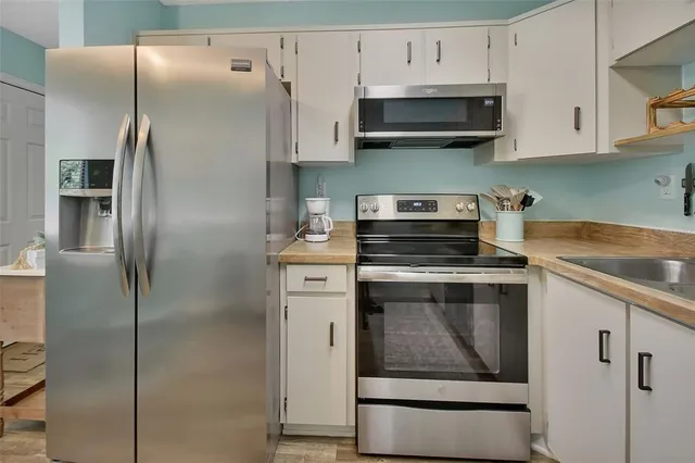 a kitchen with stainless steel appliances granite countertop a refrigerator a stove and a sink
