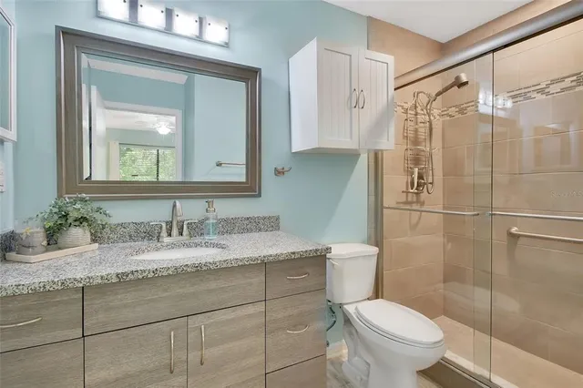 a bathroom with a granite countertop sink toilet and shower