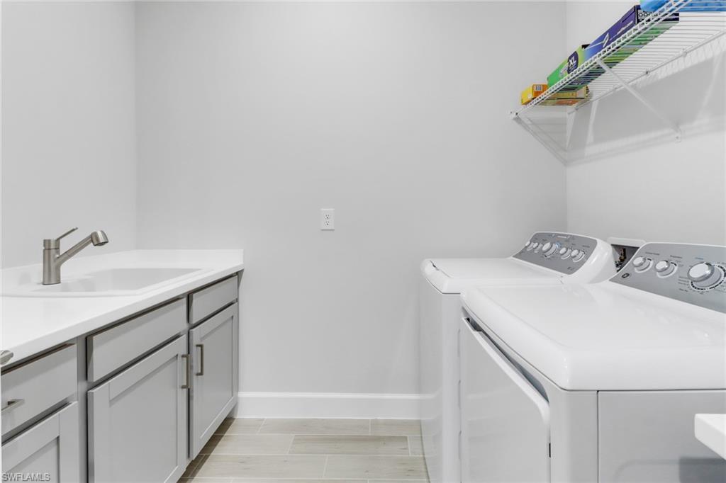 15561 Vittorio Street Naples, FL 34114 - Photo 14 of 16 Laundry area featuring a sink, baseboards, cabinet space, and washer and dryer