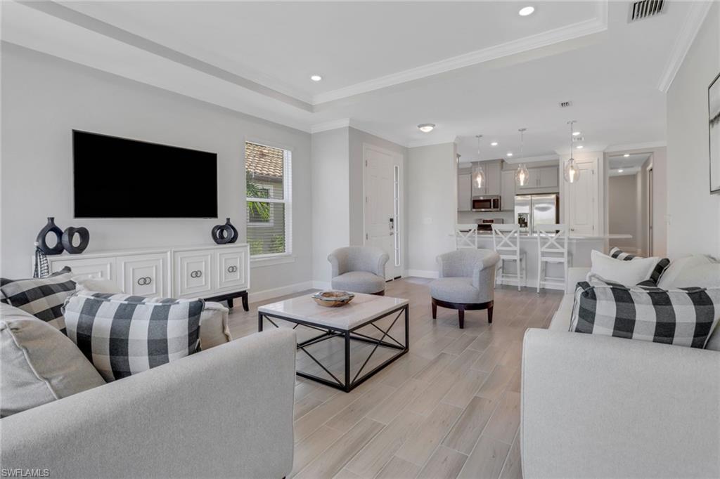 15561 Vittorio Street Naples, FL 34114 - Photo 5 of 16 Living room featuring visible vents, a tray ceiling, and ornamental molding