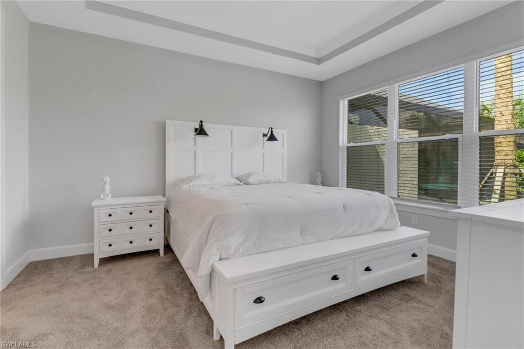 15561 Vittorio Street Naples, FL 34114 - Photo 8 of 16 Bedroom with a tray ceiling, baseboards, and light colored carpet