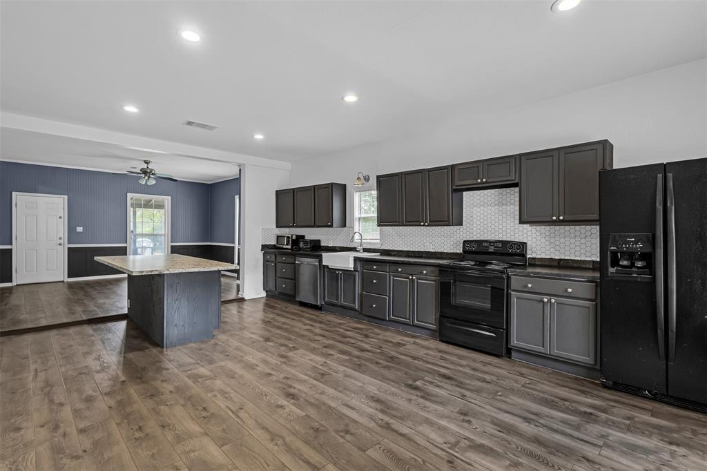 100 West Munson Street Denison, TX 75021 - Photo 4 of 12 a kitchen with stainless steel appliances kitchen island granite countertop a stove a sink dishwasher a refrigerator and a microwave