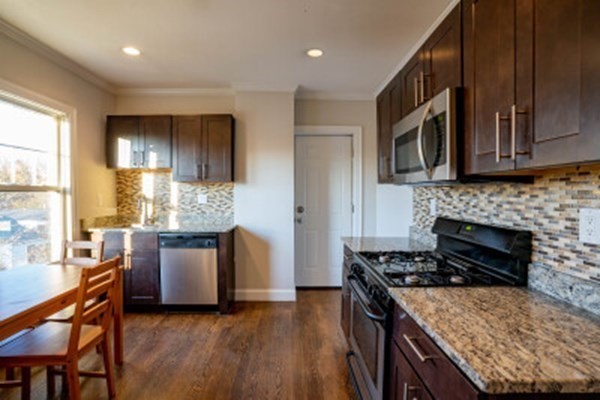 a kitchen with kitchen island granite countertop wooden cabinets a sink and a stove