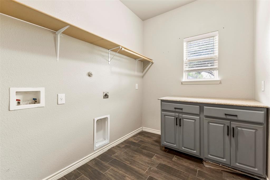 6522 Portside Ridge Lane Dallas, TX 75249 - Photo 26 of 37 Laundry room featuring wood-finish tile flooring, built-in shelving, a window with blinds, and built-in cabinetry with a countertop