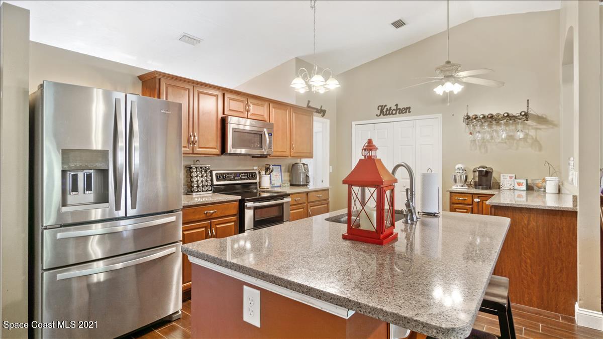 7220 Freeport Road Cocoa, FL 32927 - Photo 11 of 25 a kitchen with stainless steel appliances granite countertop a refrigerator a stove top oven a dining table and chairs