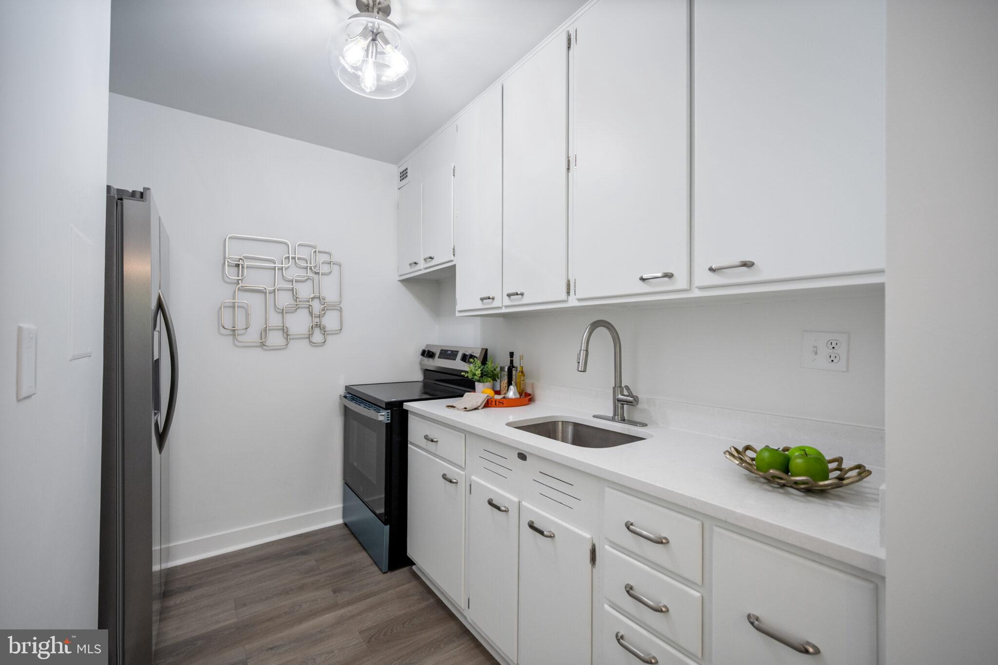 4101 Cathedral Avenue Northwest, Unit 616 Washington, DC 20016 - Photo 9 of 27 a kitchen with stainless steel appliances granite countertop a refrigerator sink and white cabinets