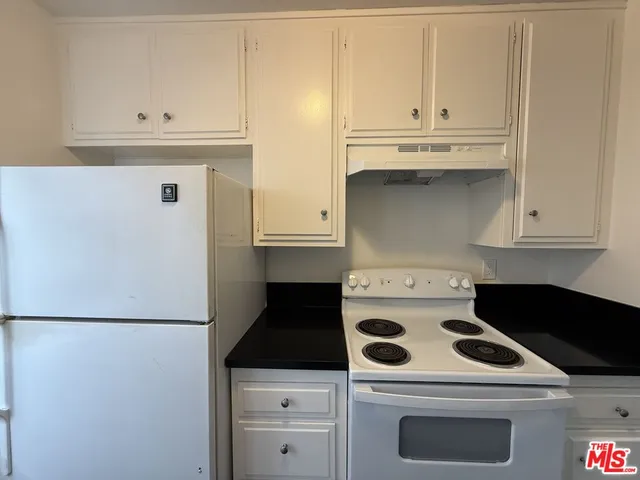 a kitchen with white cabinets and white appliances