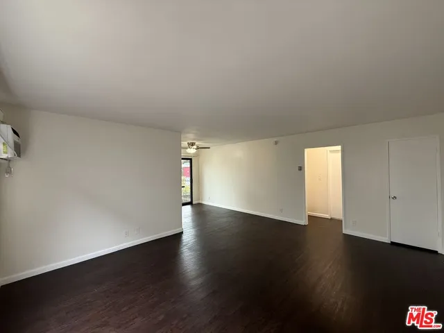 an empty room with wooden floor and window