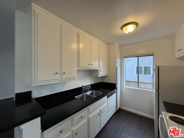 a kitchen with granite countertop white cabinets and black appliances