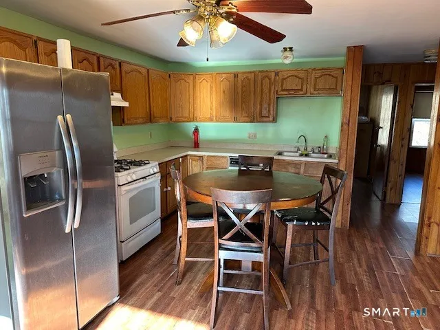 a kitchen with stainless steel appliances kitchen island granite countertop a table chairs and a refrigerator