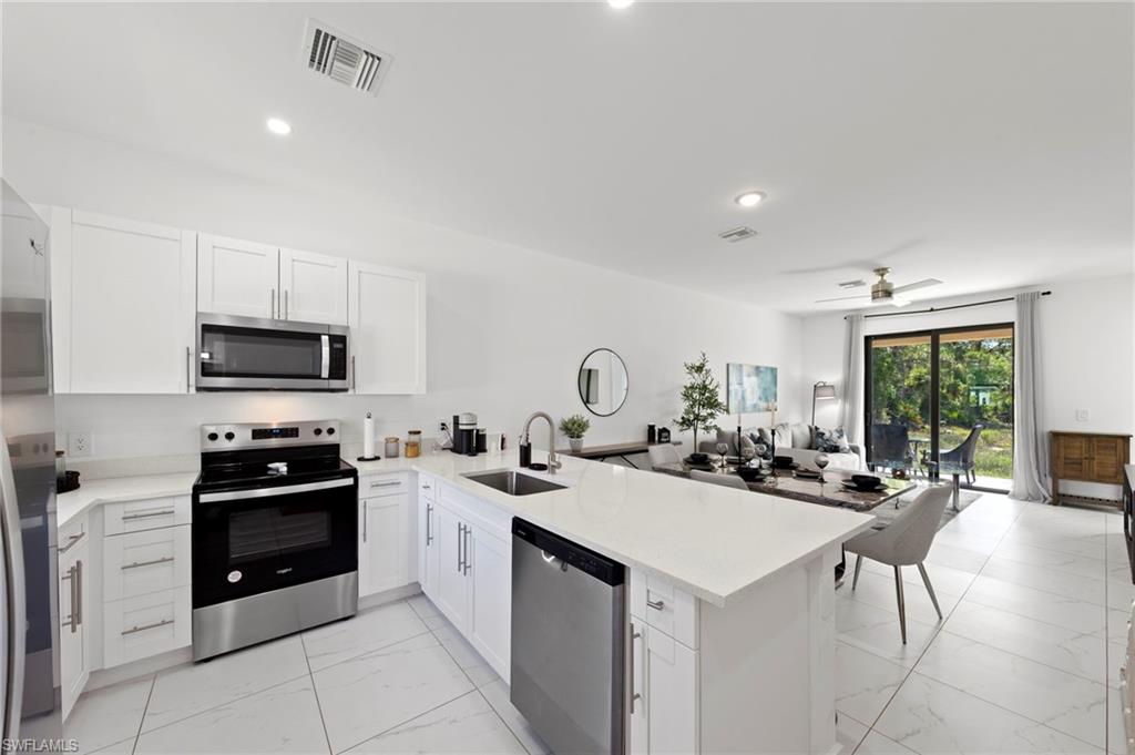 907 Homestead Road South Lehigh Acres, FL 33974 - Photo 7 of 29 a kitchen with a sink a stove top oven and cabinets