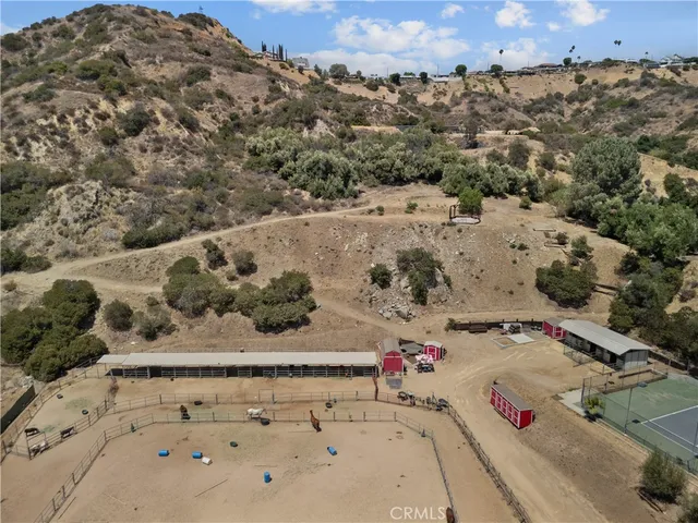 an aerial view of a house with a yard and covered with trees