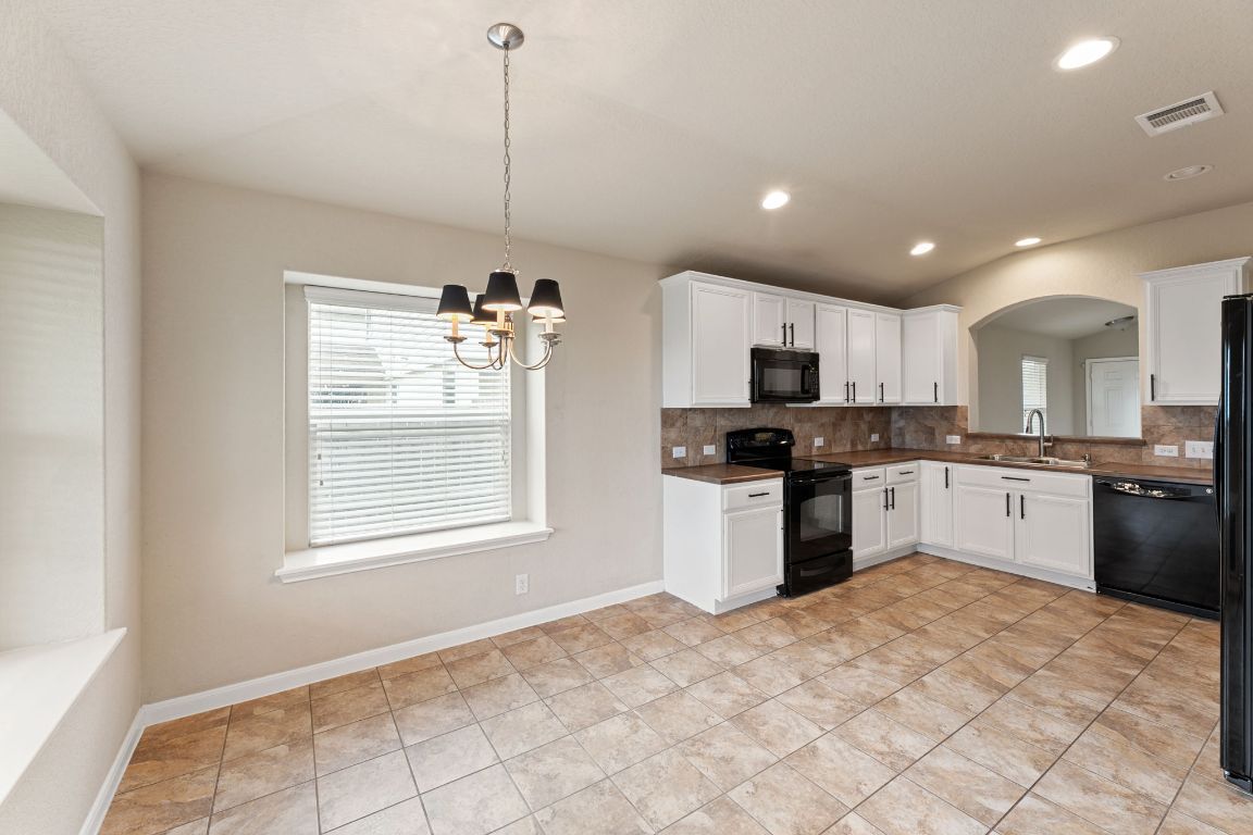 582 Briggs Drive New Braunfels, TX 78130 - Photo 14 of 32 a kitchen with granite countertop a refrigerator and microwave