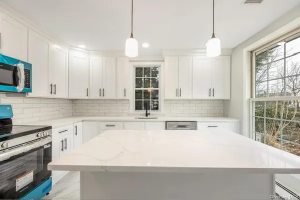 a kitchen with stainless steel appliances granite countertop a stove a sink and a white cabinets