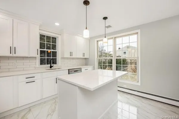 a kitchen with a stove a sink a center island and windows