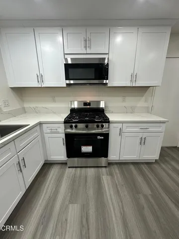 a kitchen with stainless steel appliances granite countertop a stove a sink and a microwave