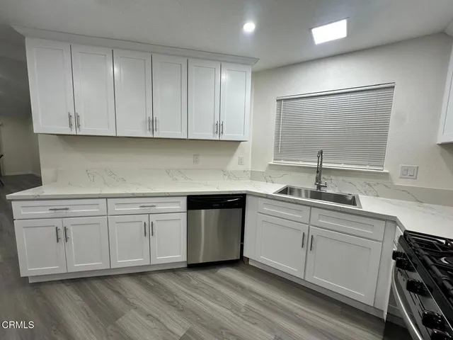 a kitchen with stainless steel appliances granite countertop a sink and cabinets with wooden floors