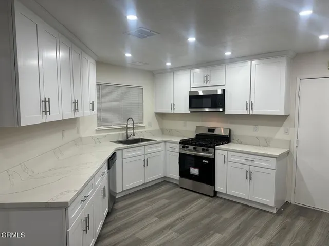a kitchen with granite countertop a stove top oven sink and cabinets