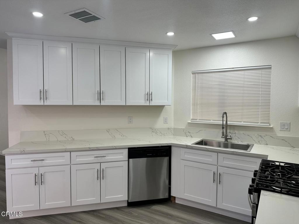 44839 16th Street East Lancaster, CA 93535 - Photo 20 of 53 a kitchen with white cabinets white appliances sink and dishwasher with wooden floor