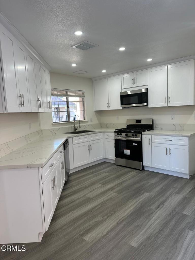 44839 16th Street East Lancaster, CA 93535 - Photo 21 of 53 a large kitchen with stainless steel appliances granite countertop a stove a sink dishwasher and a microwave