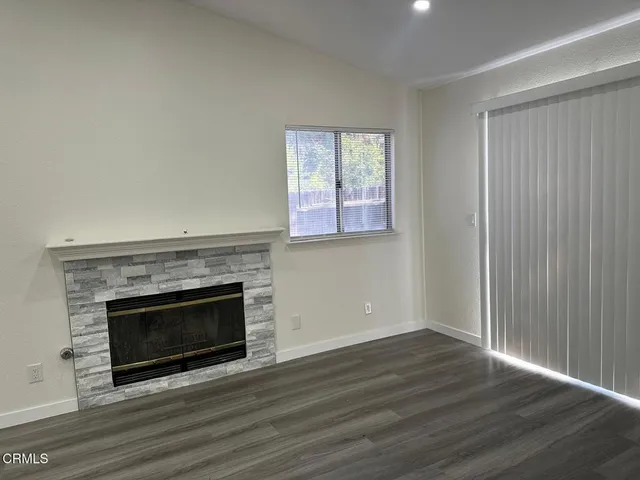 an empty room with wooden floor fireplace and windows