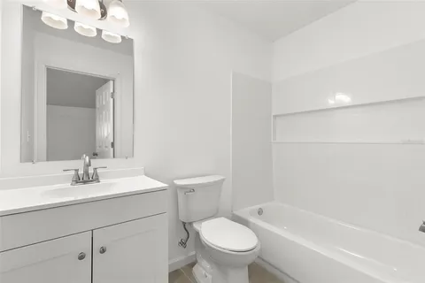 a bathroom with a sink a toilet a mirror a vanity and bathtub