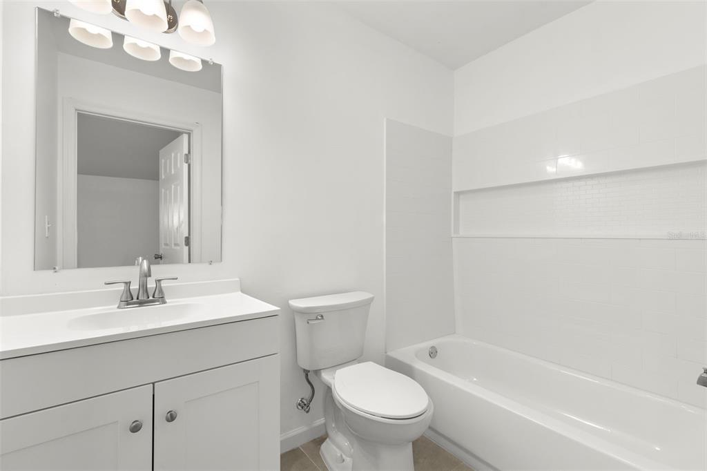 3723 Temple Street Tampa, FL 33619 - Photo 12 of 28 a bathroom with a sink a toilet a mirror a vanity and bathtub