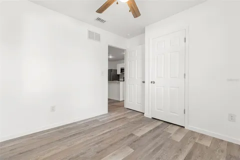 an empty room with ceiling fan and wooden floor