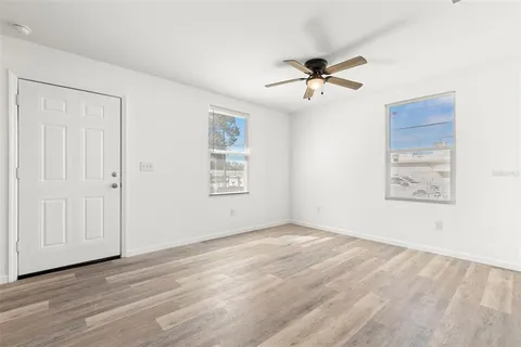 an empty room with windows and fan