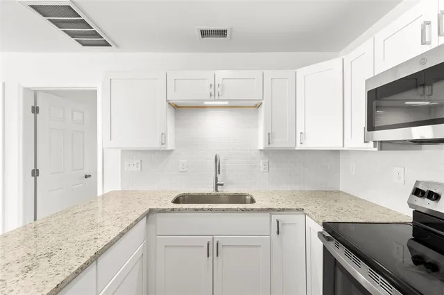 a kitchen with kitchen island granite countertop a sink a stove and cabinets