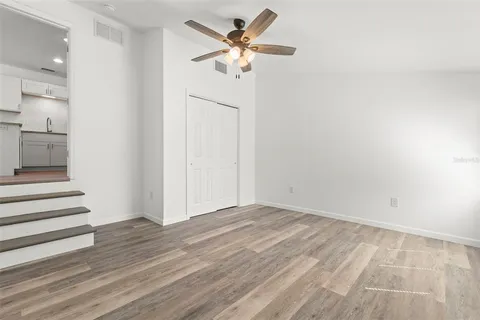 a view of a room with wooden floor and a ceiling fan