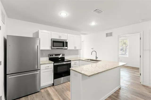 a kitchen with granite countertop a refrigerator stove and sink