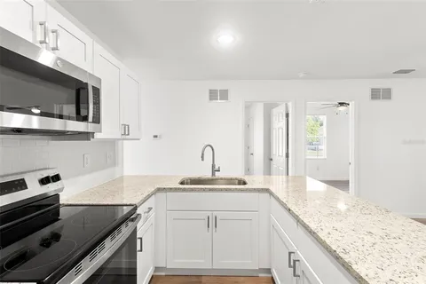 a kitchen with granite countertop a sink stainless steel appliances and white cabinets