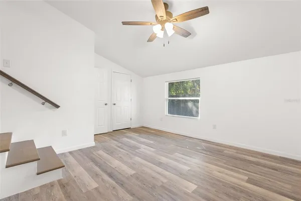 an empty room with wooden floor fan and windows